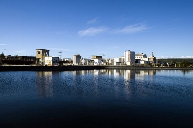 Vista de lago, com parte do complexo nuclear de Caetité ao fundo