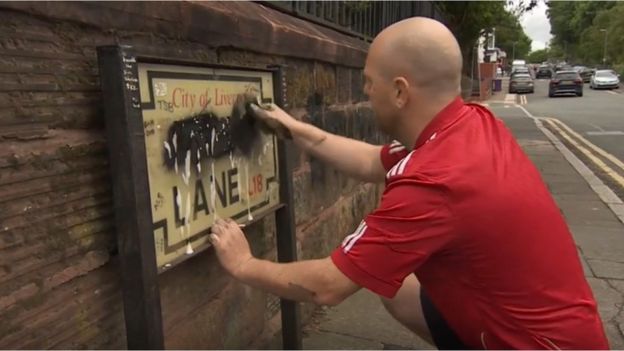 Emmett O'Neill cleaning a Penny Lane sign