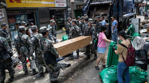 澳门内港十月初五街一名女士掩鼻走过解放军驻军正在清理的垃圾堆（25/8/2017）