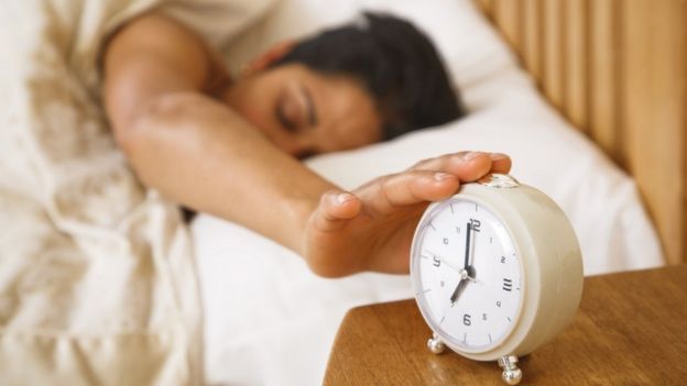A woman hits an alarm clock