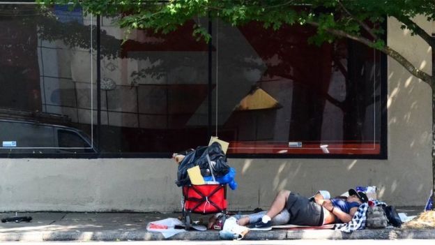 Imagem mostra homem sem teto deitado em uma calçada em Portland, nos Estados Unidos