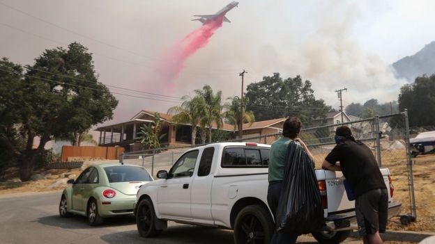 A firefighting aircraft drops fire retardant as the Holy Fire burns near homes on August 10, 2018 in Lake Elsinore, California