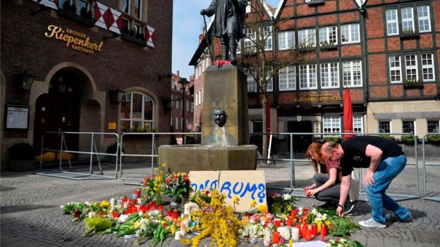 Well wishers place flowers and candles next to the statute near the scene of the crime