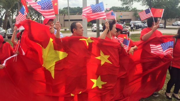 A group of China supporters wave Chinese and US flags as they wait for the arrival of Chinese President Xi Jinping at Palm Beach international airport on April 06 2017