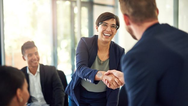 Una mujer le da la mano a un hombre durante una reunión empresarial