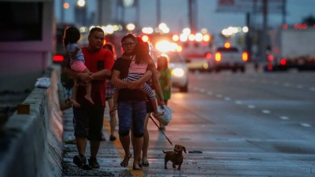 A family with children, parents and dog in tow, walks along Interstate 45 while escaping flood waters from Tropical Storm Harvey in Houston