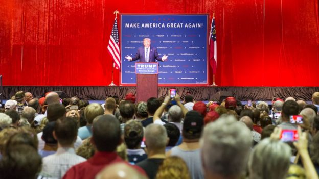 Trump discursa no palanque, observado por dezenas de pessoas