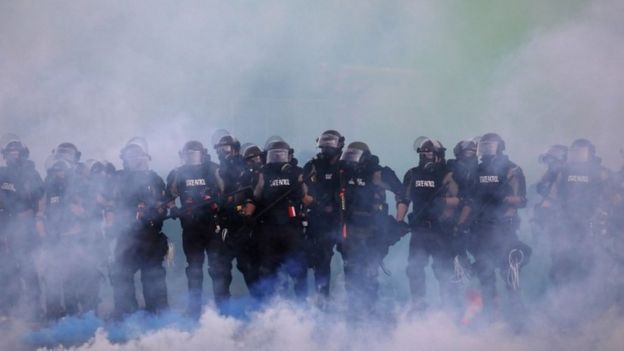 Oficiales de policía caminan a través de gases lacrimógenos en Minnesota