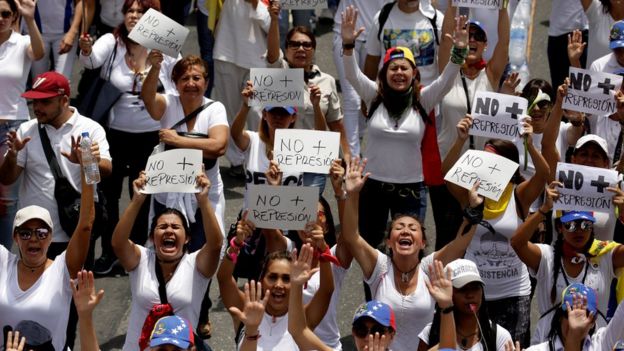 Mujeres protestan con las manos en alto en Venezuela.