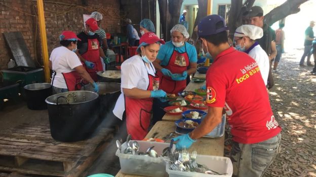 Volunteers serve food to people in a church in Cúcuta
