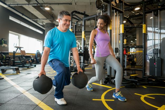 Hombre y mujer haciendo ejercicios para piernas en un gimnasio