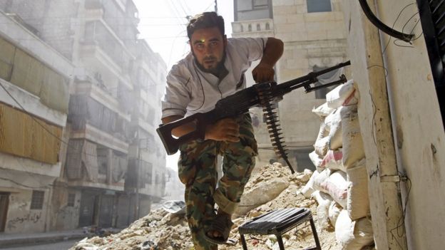 A rebel fighter takes cover during clashes with the Syrian army in the Salahuddin district of Aleppo (7 August 2012)