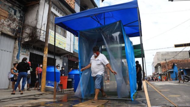 Persona atraviesa un puesto improvisado de desinfección