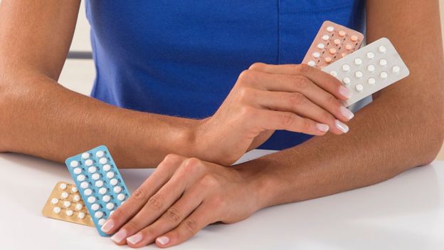 Manos de mujer con pastillas anticonceptivas.