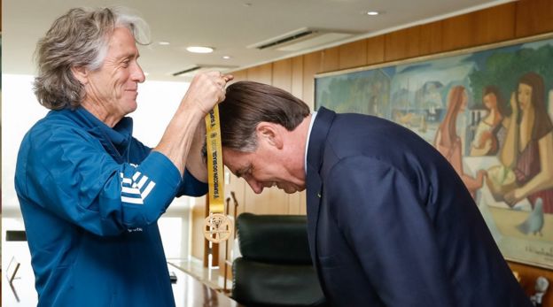 Técnico do Flamengo, Jorge Jesus, colocando medalha em Jair Bolsonaro; nos últimos meses, o clube carioca se aproximou do presidente