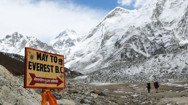 Dos montañistas en una ruta hacia la cumbre del Everest y un cartel que señala "Camino hacia el Everest"