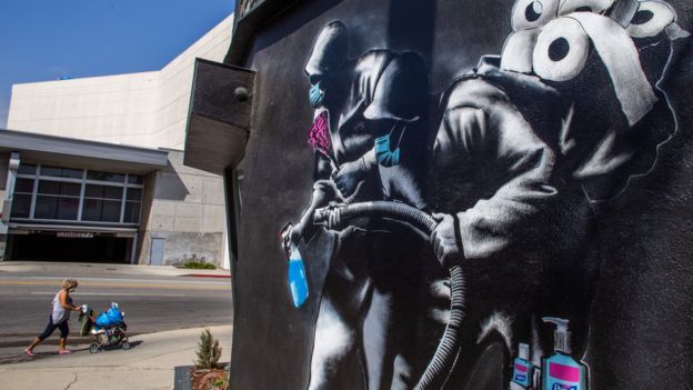 Un mural en California de dos personas con gel desinfectante y papel higiénico.