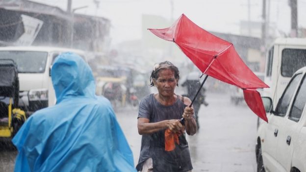 A woman clutches an umbrella amid heavy rain in the Philippines