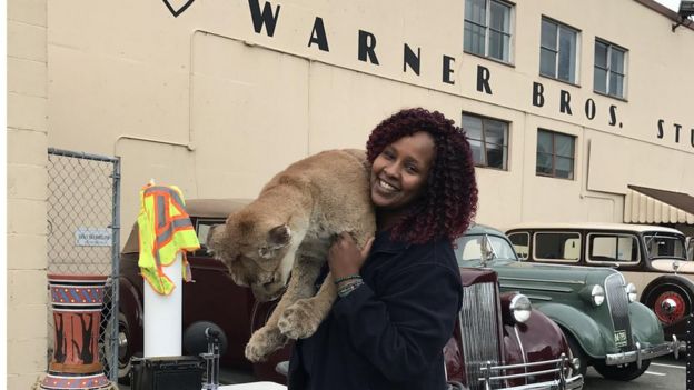 Ubah Mohamed carrying a lion cub outside a cinema studio