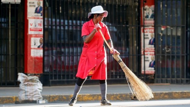 A woman sweeps the street outside the opposition Movement for Democratic Change (MDC) headquarters in Harare, Zimbabwe, 2 August 2018