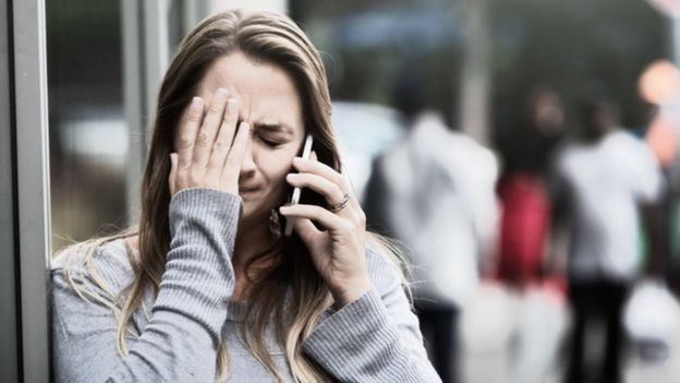 Una mujer se tapa la cara con un teléfono en la mano (imagen ilustrativa)