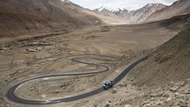 Workers ride on the back of a truck along Pangong Lake road in northern India's Ladakh region