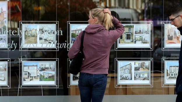 A woman looks in an estate agent's window in London