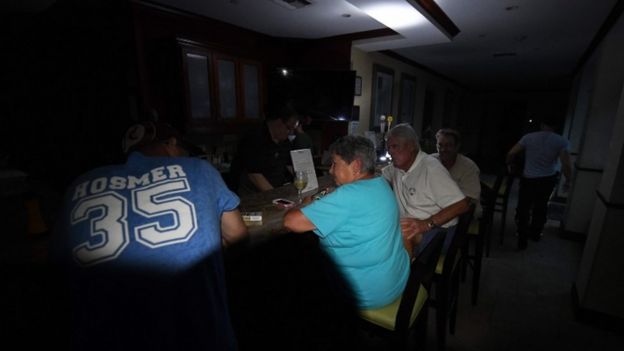 Local residents sit at the bar in the dark after a citywide power failure as Hurricane Harvey hit Corpus Christi, Texas, on August 25, 2017