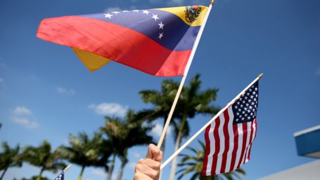 una persona sostiene las banderas de Venezuela y Estados Unidos