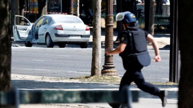 A French gendarme runs past a car on the Champs Elysees avenue after an incident in Paris, France, on 19 June 2017.