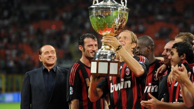Berlusconi stands with AC Milan players holding up a trophy in 2008