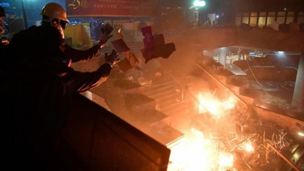 Anti-government protesters throw paper to fuel a large fire started by other protesters in a staircase at the main entrance