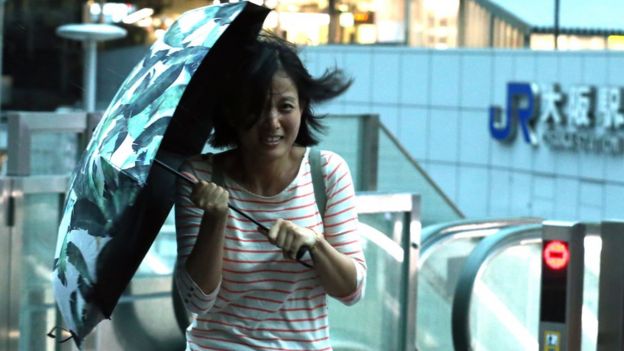 Woman carrying an umbrella battles against strong winds