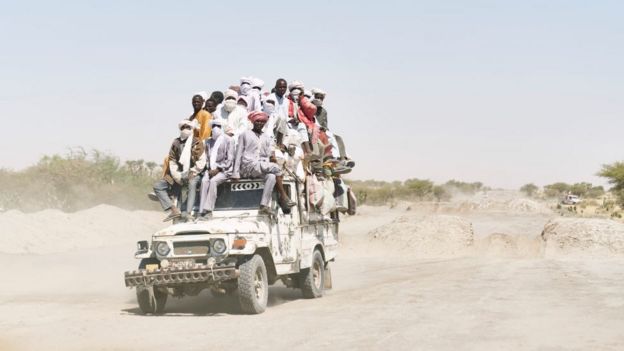 Migrantes en una camioneta en el desierto.