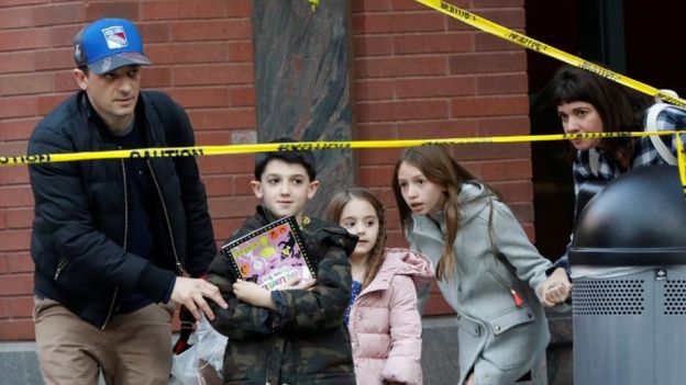 Niños y adultos pasan por los cordones policiales