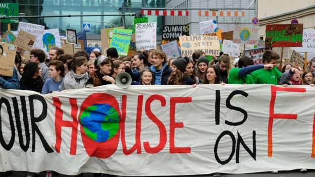 Adolescentes con pancartas exigiendo acciones urgentes contra el cambio climático