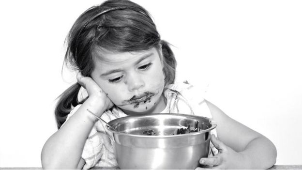 Niña triste comiendo una mezcla de tarta.