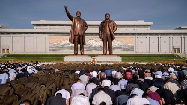 Gente haciendo reverencia ante las estatuas de Kim Jong-il y Kim Il-sung