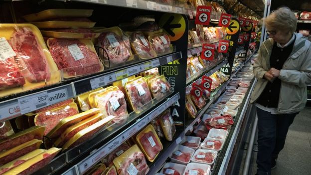 Consumidora olha gôndola de carnes no supermercado