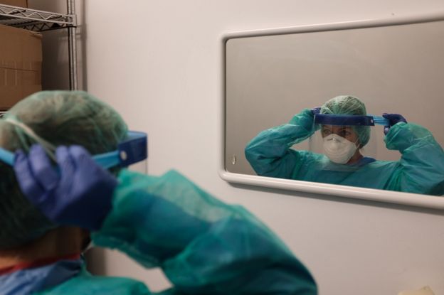 A hospital worker puts on a protective visor