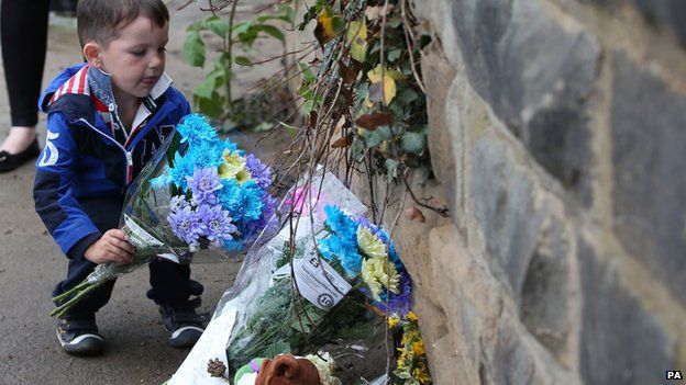 Finlay Bolton, 4, places flowers next to a wall