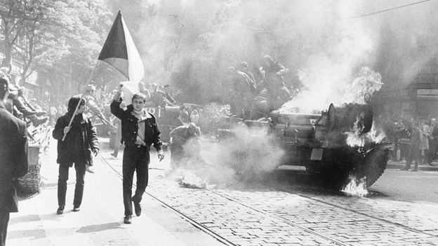 Чешские студенты с флагом возле горящего танка.