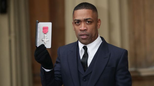 Wiley, also known as Richard Cowie, poses with his medal after being appointed an MBE in 2018