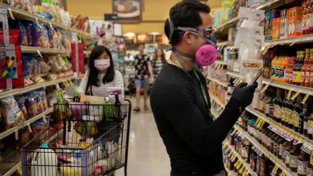 Instacart employee Eric Cohn, 34, searches for an item for a delivery order while wearing a respirator mask to help protect himself, Tucson, Arizona, 4 April 2020