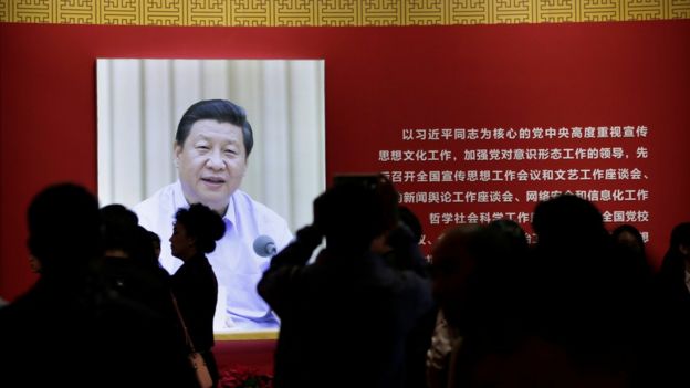 Periodistas frente a una imagen de Xi Jinping