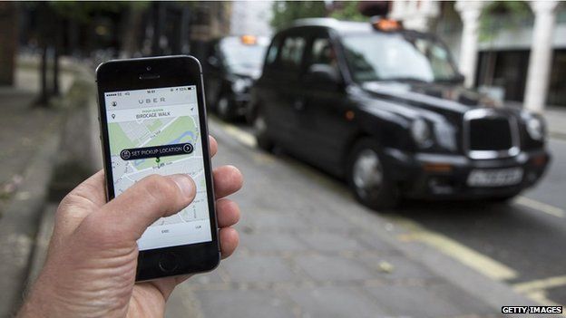 Uber app on the phone near London black cab