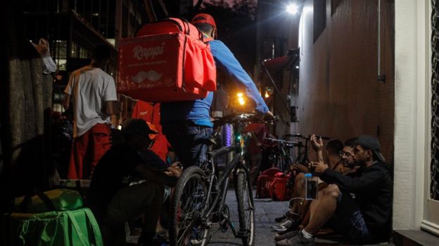 Na região da rua Augusta, centro de São Paulo, entregadores de aplicativos aguardam pedidos em calçada