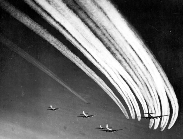 Foto em preto e branco mostra imagem de aviões deixando rastro de fumaça no céu, na época da segunda guerra