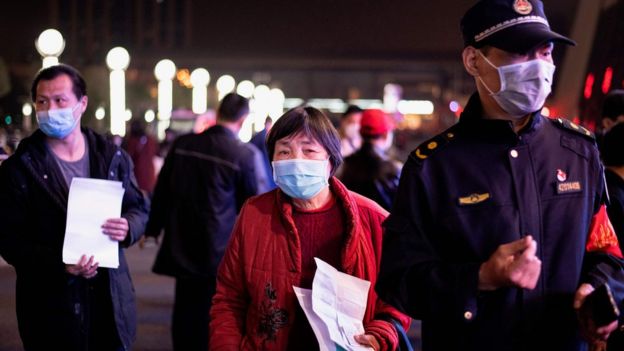 Passengers wear facemasks as they form a queue at the Wuhan Wuchang Railway Station in Wuhan, early on April 8, 2020