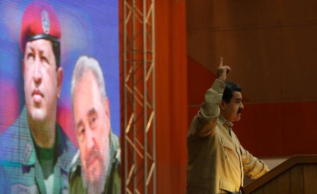 Maduro frente a un cuadro de Chávez y Fidel Castro